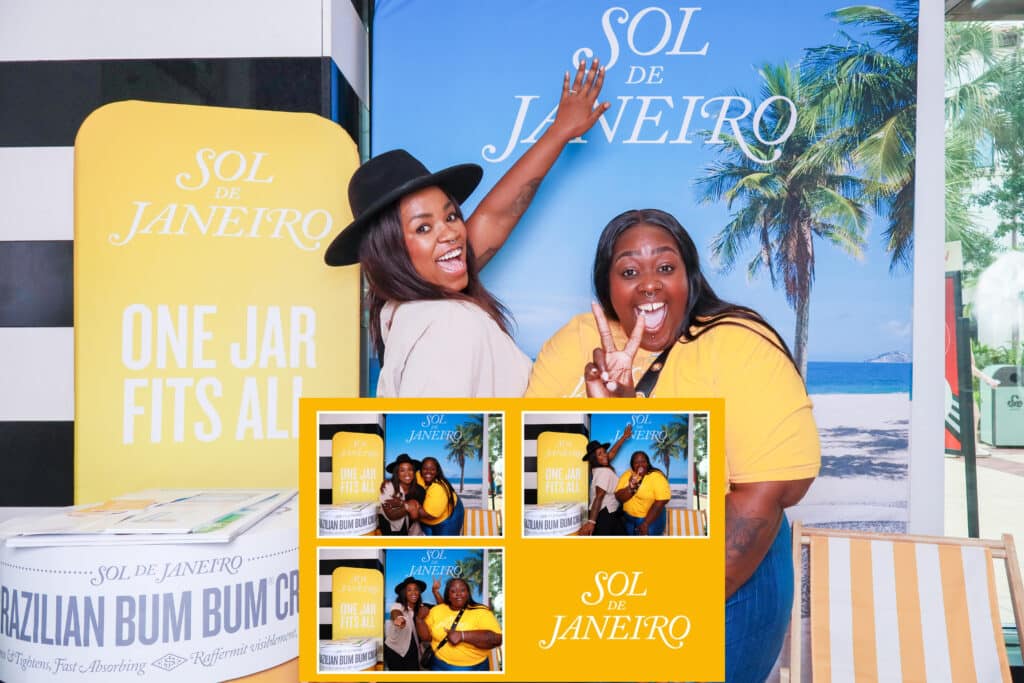 Two women smile and pose excitedly in front of a tropical-themed Sol de Janeiro sign, with a branded display and product stand beside them. Four smaller Digital Photo Booth images are inset at the bottom.