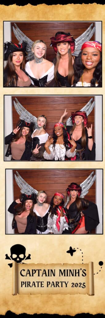 Four women in pirate costumes strike playful poses and hand signs in a Digital Photo Booth, standing before a wooden backdrop with silver wings at Captain Minh&rsquo;s Pirate Party 2025.