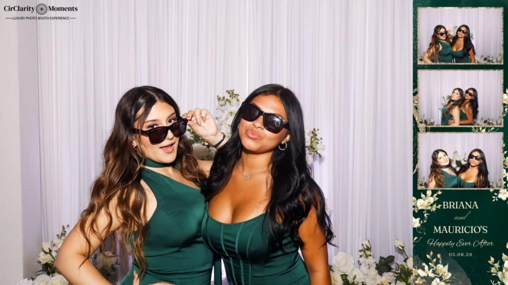 Two women in dark green dresses and sunglasses pose before a floral backdrop. To the right, a Digital Photo Booth strip features playful snapshots labeled BRIANA and MAURICIO'S Happily Ever After 01.06.24.