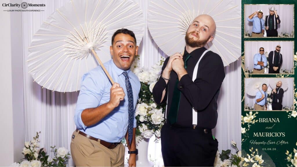 Two men pose playfully with large white parasols in front of a floral backdrop. A Digital Photo Booth strip on the right captures their funny faces and poses at Briana and Mauricio's wedding.